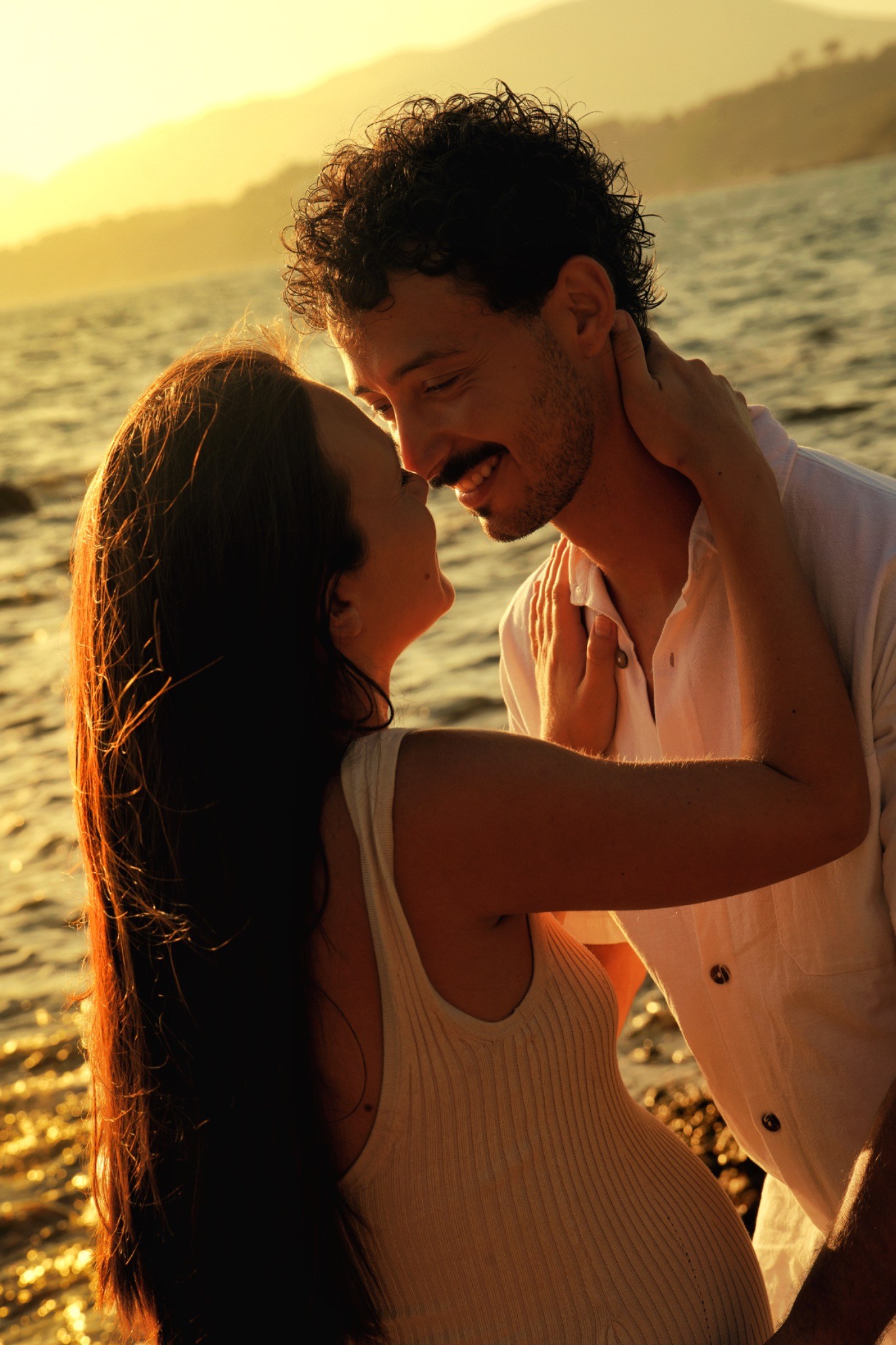 Un couple s’enlace au bord de la mer au coucher du soleil