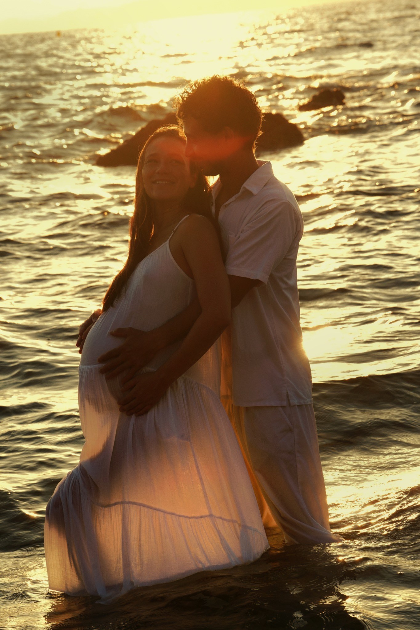 Un couple attend un enfant face à la mer dorée