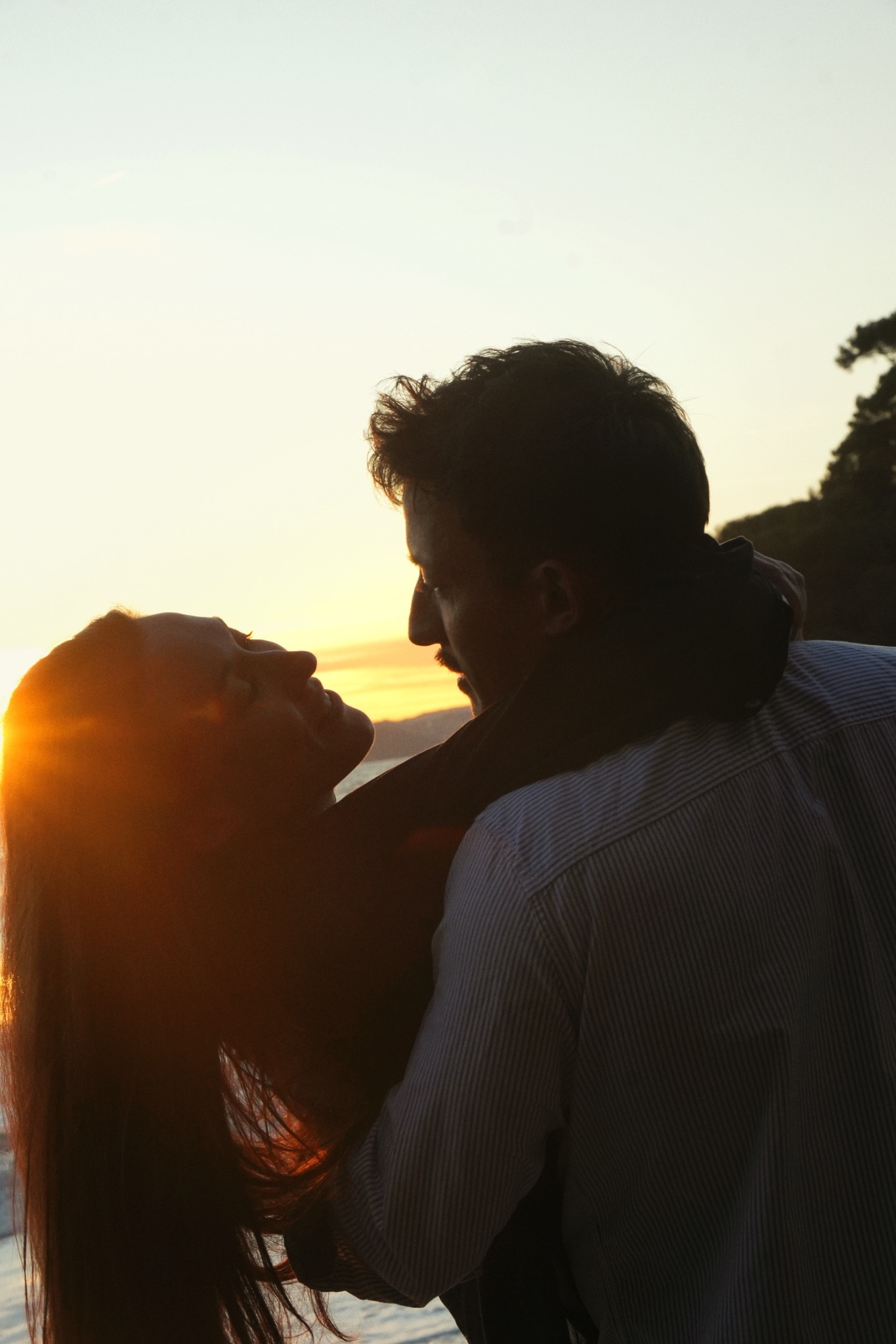 Un couple s’enlace dans un contre-jour doré