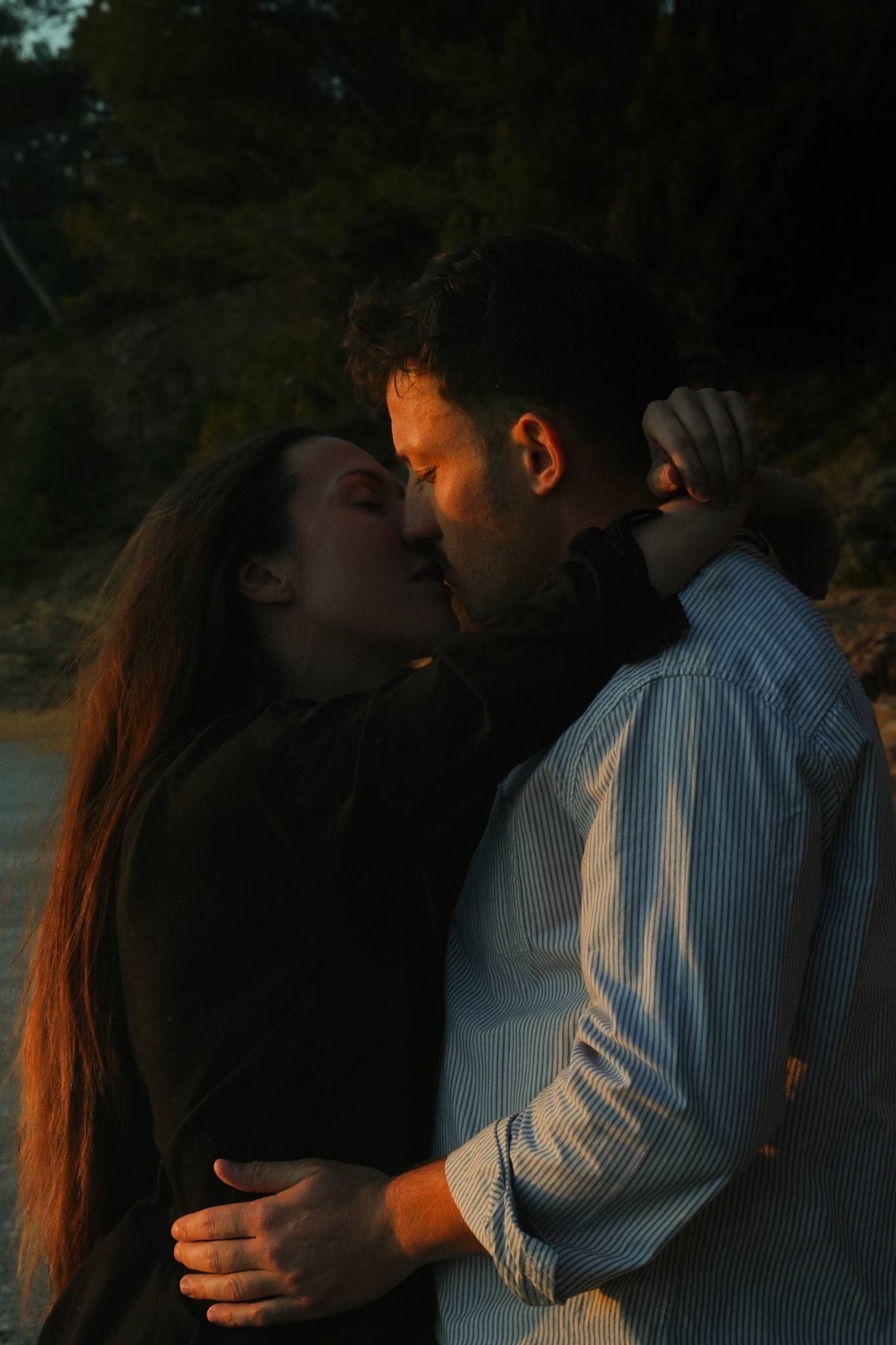 Un couple s’embrasse dans une lumière douce en fin de journée