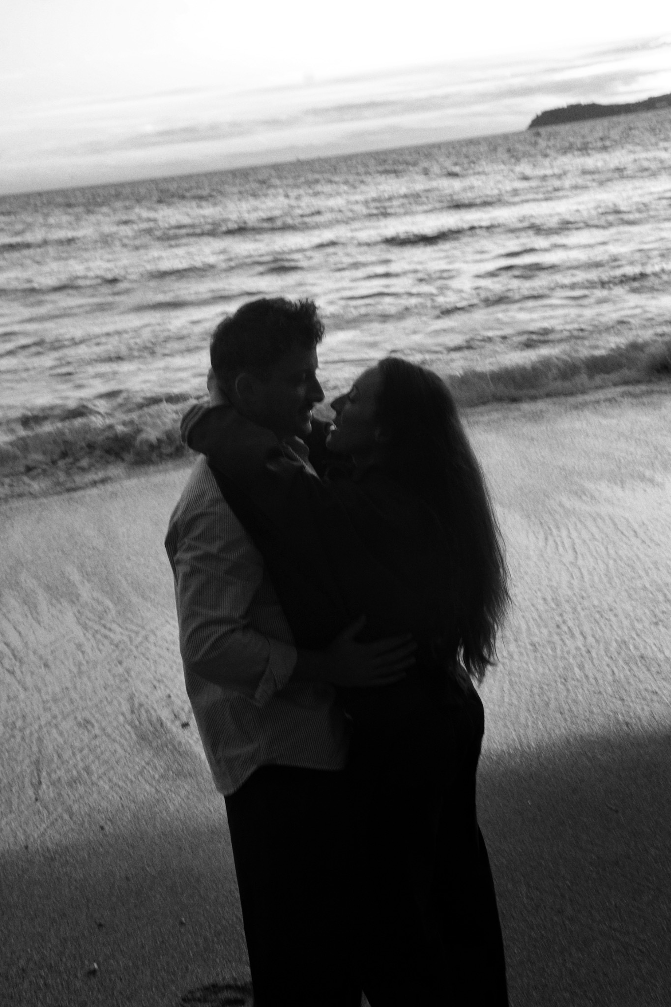 Un couple enlacé face à la mer en noir et blanc