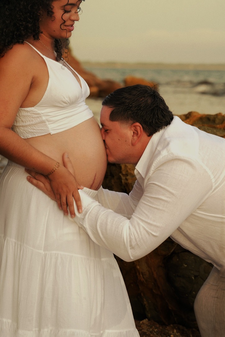 Un futur père embrasse le ventre de sa compagne enceinte