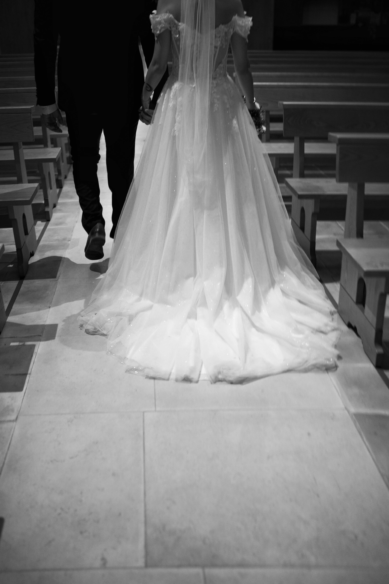 La mariée remonte l’allée vers la cérémonie, photographiée en noir et blanc