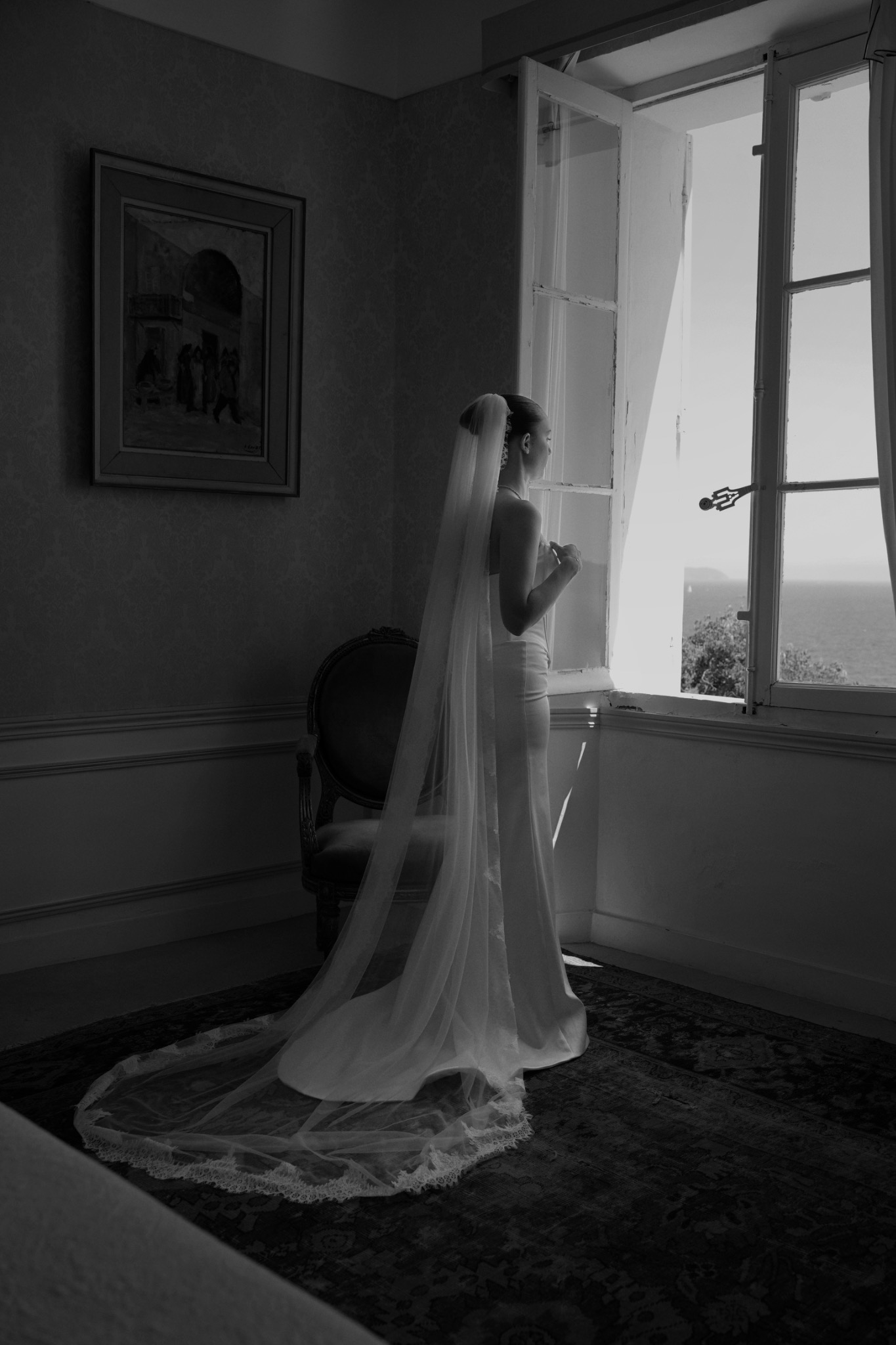 La mariée en robe se tient près de la fenêtre
