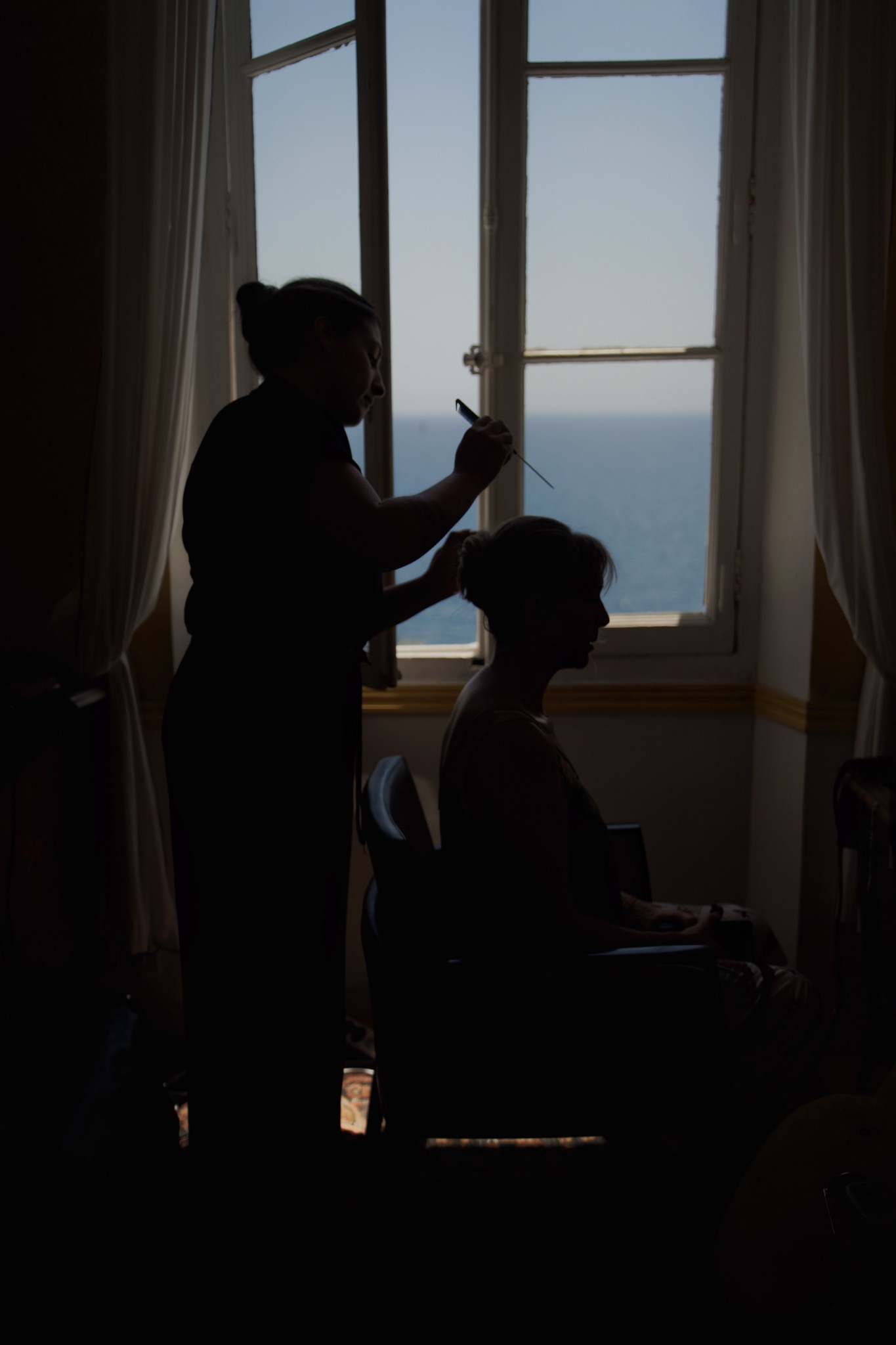 La mariée se prépare près d’une fenêtre, dans la lumière du jour