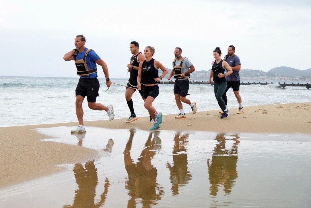 Des coureurs franchissent ensemble la ligne d’eau sur la plage.